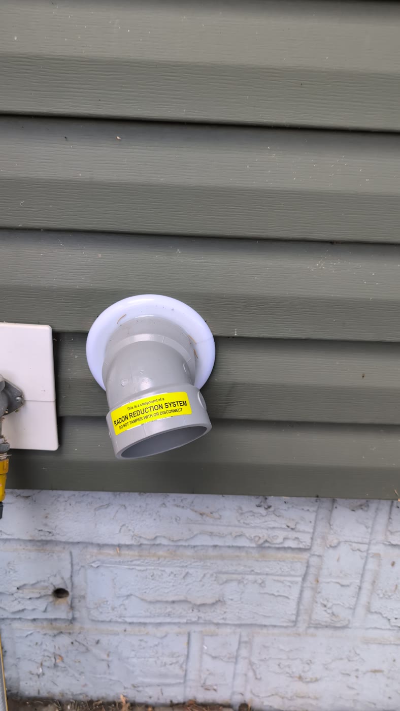 The radon system's exhaust pipe coming out the side of the house, labelled as a radon reduction system.
